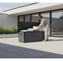 Frau verstaut Kissen in einer grauen Gartenbox im Außenbereich