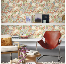Wohnraum mit floral gemusterter Tapete, Regalen, Sesseln und Dekorationen für eine wohnliche Atmosphäre