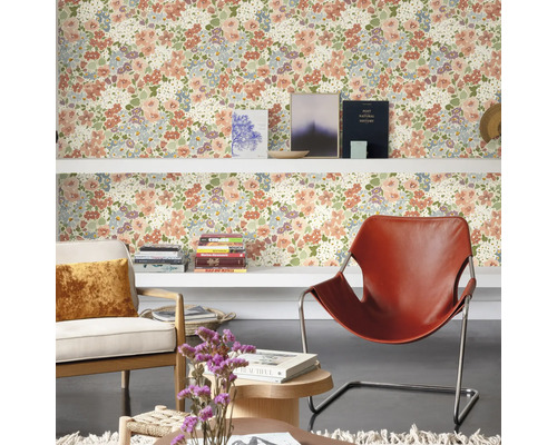 Wohnraum mit floral gemusterter Tapete, Regalen, Sesseln und Dekorationen für eine wohnliche Atmosphäre