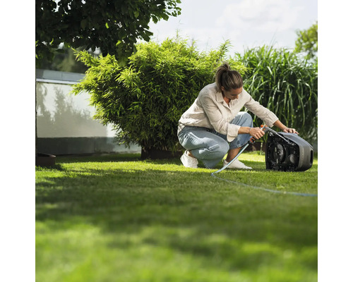 Frau benutzt eine Gardena Schlauchtrommel im Garten für die Bewässerung.
