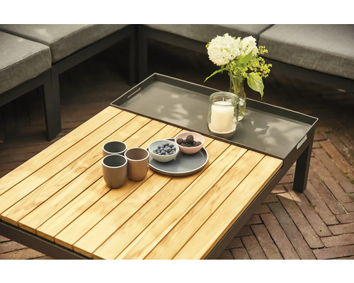 Gartentisch mit Holzplatte, Getränken, Kerze und Blumen auf einer Terrasse