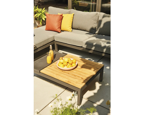 Gartenszene mit grauer Loungegarnitur, Holztisch, Obstschale und Getränken