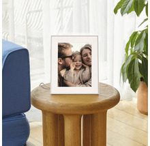 Digitaler Bilderrahmen auf einem runden Holzbeistelltisch im Wohnzimmer, zeigt ein Familienfoto