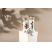 Zwei Grabkerzen mit Blumenmuster auf einem weißen Sockel