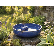 Blaue Vogeltränke mit Vogelfiguren auf Baumstumpf im Garten