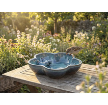 Vogeltränke aus Keramik mit Vogeldekoration auf Holztisch im Garten