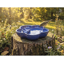 Vogeltränke aus Keramik mit Vogelmotiv auf Baumstumpf im Garten