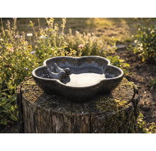 Keramik Vogeltränke mit zwei Vogel Figuren auf einem Baumstumpf im Garten.