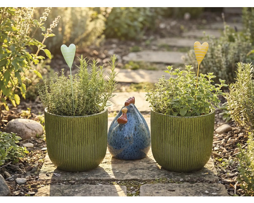 Gartenstillleben mit bepflanzten Töpfen, Herzsteckern und Dekohuhn auf einem Steinweg