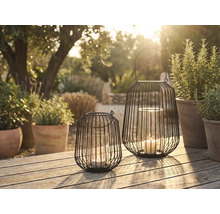 Zwei dekorative Windlichter aus Metall mit Glaseinsatz und Kerze auf einem Gartentisch