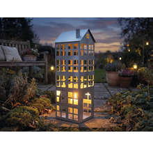 Dekorative Laterne in Hausform mit Kerze im Garten.