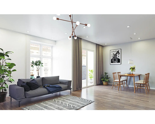 Helles Wohn- und Esszimmer mit grauem Sofa, Holzesstisch, gemustertem Teppich und moderner Deckenleuchte.