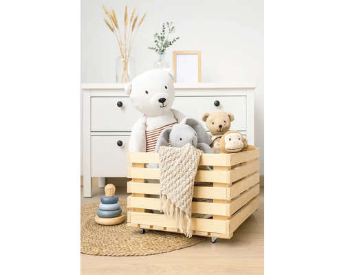 Holzkiste mit Spielzeugbären, Hase und Affe auf einem Teppich vor einer Kommode