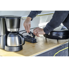 Eine Person schliesst eine Kaffeemaschine an eine Mehrfachsteckdose an.