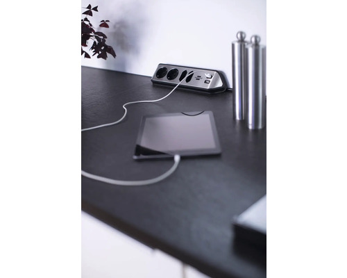 Steckdosenleiste mit USB-Anschlüssen und angeschlossenem Tablet auf einem Tisch