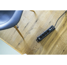 Steckdosenleiste mit Überspannungsschutz und Schalter auf Holzboden.