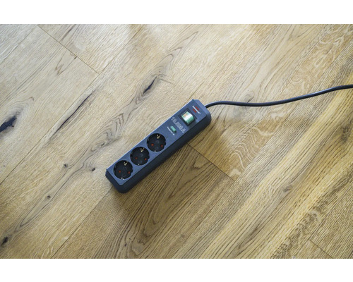 Steckdosenleiste mit drei Steckplätzen und Überspannungsschutz auf Holzboden