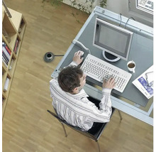 Blick von oben auf eine Person, die an einem Schreibtisch mit Computer, Tastatur und Maus arbeitet.