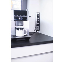 Steckdosenleiste mit fünf Steckdosen und zwei USB-Anschlüssen neben einer Kaffeemaschine auf einer Arbeitsplatte