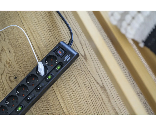 Mehrfachsteckdose mit Schalter und eingestecktem USB-Kabel auf einem Holzboden