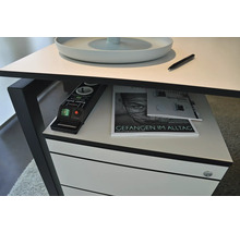 Detailansicht eines Schreibtisches mit Mehrfachsteckdose, Zeitschriften und einem Stift