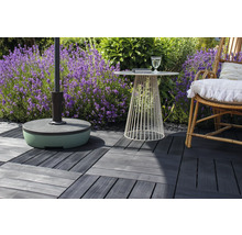 Terrassenszene mit Sonnenschirmständer, kleinem Tisch, Stuhl und Terrassenfliesen