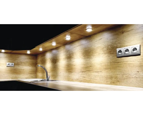 Moderne Küche mit Rückwand in Holzoptik, LED-Unterbauleuchten beleuchten eine Arbeitsplatte mit Spülbecken und verchromter Armatur.