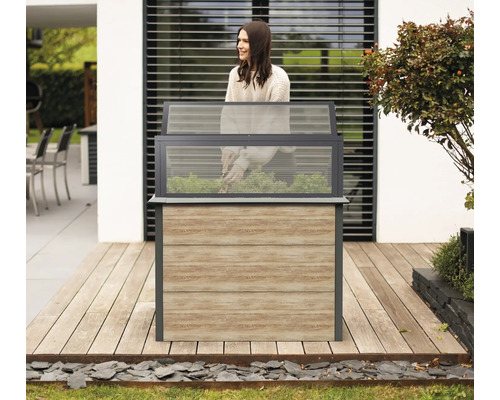 Hochbeet aus Holz und Glas im Garten mit Gärtnerin.