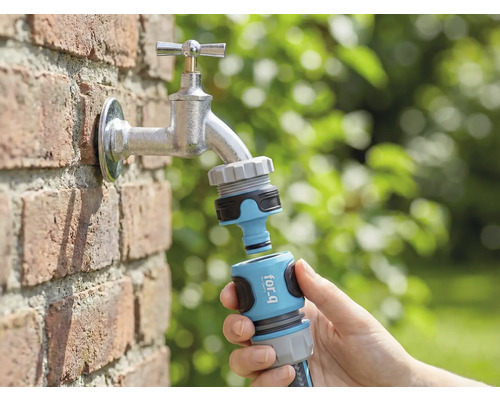 Gartenszene mit Wasserhahn, daran angeschlossen ein for_q Gartenschlauch-Kupplungsstück in der Hand