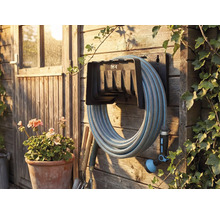 Gartenszene mit Schlauchaufroller, montiert an einer Holzwand mit Gartenschlauch