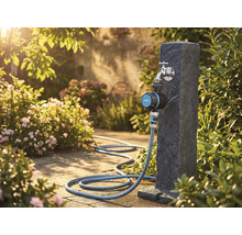Gartenszene mit Wasserhahn, Bewässerungsuhr und Gartenschlauch