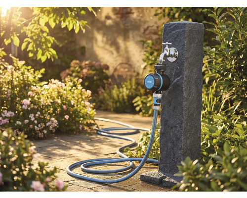 Gartenszene mit Wasserhahn, Bewässerungsuhr und Gartenschlauch