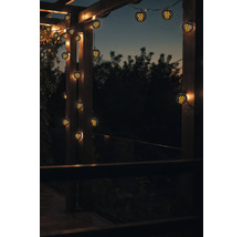 Szene mit einer Lichterkette mit kugelförmigen Lampen, die an einer Holzkonstruktion befestigt ist und eine stimmungsvolle Atmosphäre erzeugt.