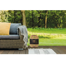 Gartenszene mit Rattan-Laterne, Outdoor-Sofa und Teppich auf einer Holzterrasse