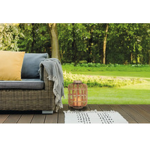 Szene mit Korblaterne, Outdoor-Sofa, Teppich und Kissen auf einer Holzterrasse