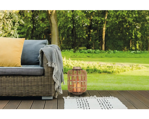 Szene mit Korblaterne, Outdoor-Sofa, Teppich und Kissen auf einer Holzterrasse