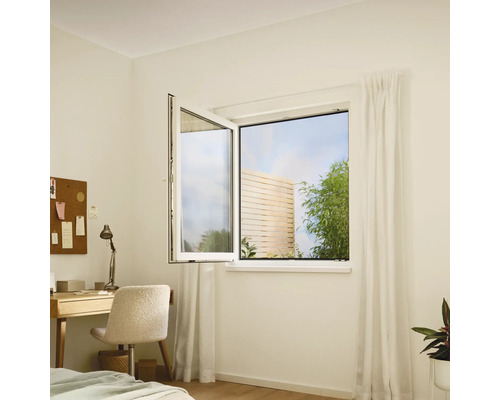 Ein geöffnetes Drehkippfenster in einem hellen Raum mit Schreibtisch und Gartenblick.