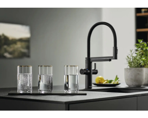 Drei Gläser mit Wasser neben einer schwarzen Küchenarmatur auf einer Küchentheke.