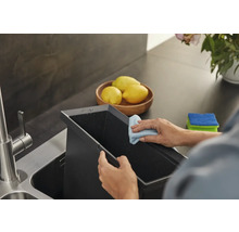 Person reinigt Spülbecken mit Putzlappen in der Küche