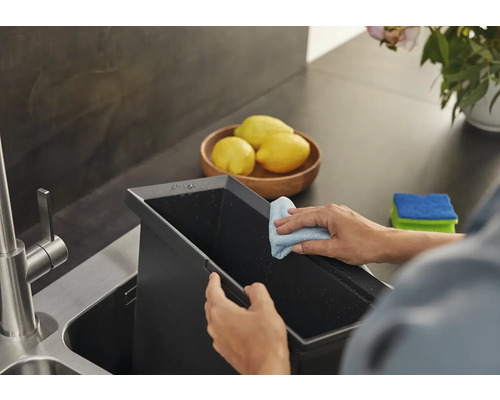 Person reinigt Spülbecken mit Putzlappen in der Küche