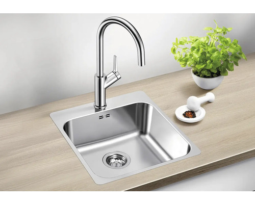 Spültisch mit Wasserhahn, Kräutertopf und Mörser auf einer Arbeitsplatte