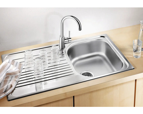 Edelstahlspüle mit Abtropffläche und Wasserhahn, darauf Gläser zum Trocknen