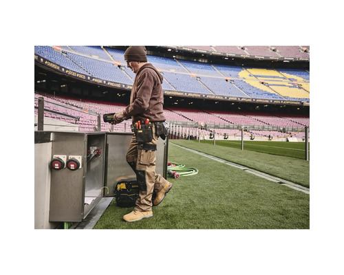 Mann mit Werkzeuggürtel und Arbeitskleidung bei der Arbeit an einem Schaltschrank im Stadion.