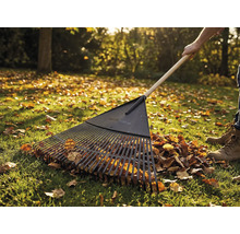 Laub-Rechen mit Holzstiel im Einsatz auf einer Rasenfläche mit Herbstlaub