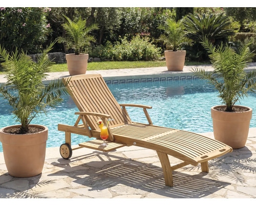 Szene mit einer Holzliege, einem Cocktail und Pflanzen neben einem Pool.