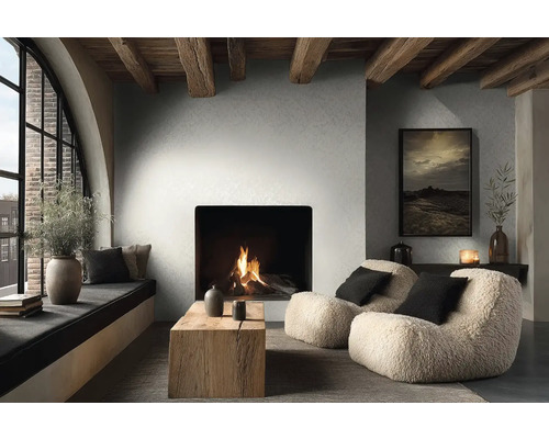 Gemütliches Wohnzimmer mit modernem Kamin, sichtbaren Holzbalken, zwei flauschigen Sesseln, rustikalem Holzcouchtisch und großem Rundbogenfenster.