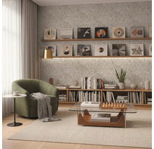 Modern eingerichtetes Zimmer mit grünem Sessel, gläsernem Couchtisch und Holzregalen vor einer grau strukturierten Tapete.
