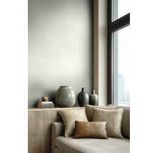 Modernes Wohnzimmer mit hellgrau gestalteter Wand, Sideboard aus Holz, dekorativen Keramikvasen und einem Sofa mit Stoff- und Lederkissen.