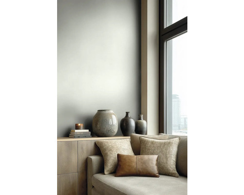 Modernes Wohnzimmer mit hellgrau gestalteter Wand, Sideboard aus Holz, dekorativen Keramikvasen und einem Sofa mit Stoff- und Lederkissen.