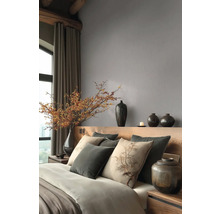 Modernes Schlafzimmer mit grauer Vliestapete, Holzkopfteil, Kissen mit Baummotiv und dekorativen dunklen Vasen.